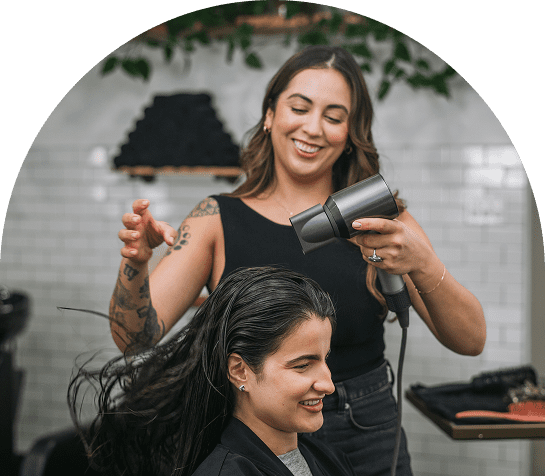 Hairdresser blow-drying woman's hair in salon.